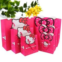 hello kitty gift bags are lined up on a white table with flowers in the background