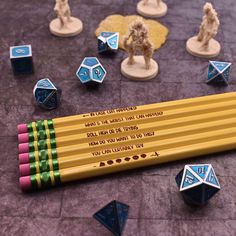 several pencils with writing on them sitting next to some dice and figurines