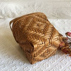 a woven basket sitting on top of a bed next to dried flowers and an empty bottle