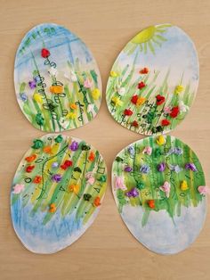 four hand painted plates with flowers on them sitting on a table next to each other