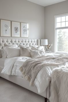 a white bed sitting in a bedroom next to a window with pictures on the wall