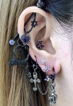 a woman wearing ear piercings with cross, heart and angel charms on her ears