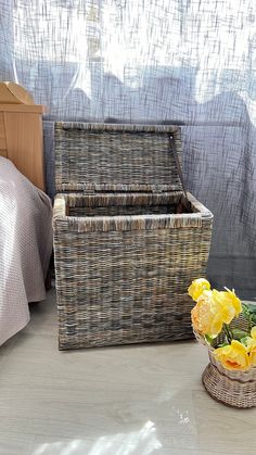 two wicker baskets sitting on the floor next to a basket with flowers in it