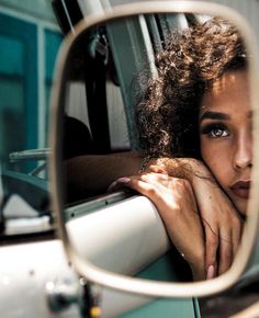 a woman's reflection in the side mirror of a car