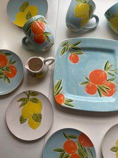 a table topped with plates and cups filled with fruit painted on them next to each other