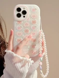 a person holding up a phone case with stickers on it and beads hanging from the back