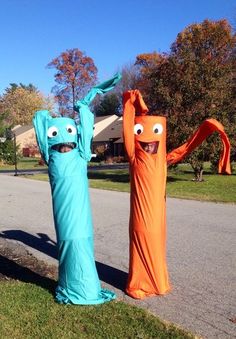 two inflatable monsters are standing on the side of the road with their arms up