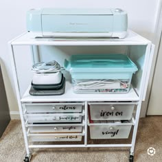 a sewing machine sitting on top of a white shelf next to drawers with plastic containers