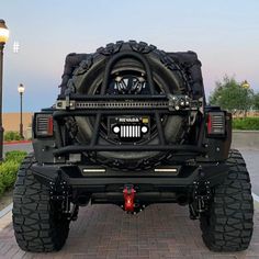 the rear end of a black truck parked in front of a parking lot at dusk