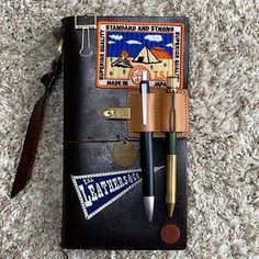 a notebook with a pen and some other items on top of it, sitting on the carpet