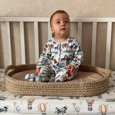 a baby sitting in a crib on top of a bed