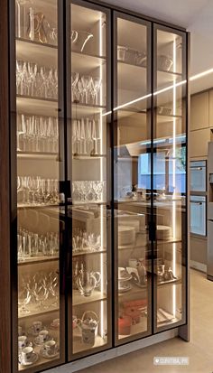 a large glass cabinet filled with lots of dishes and glasses on top of it's shelves