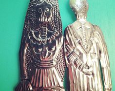 two silver figurines are standing next to each other on a green table top