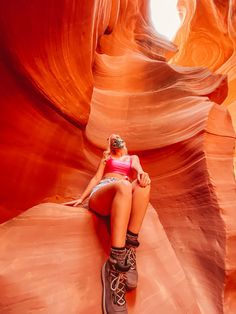 a woman sitting on top of a rock formation in the middle of a desert area