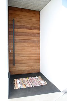 a rug is placed on the floor in front of a door with a wooden slatted design