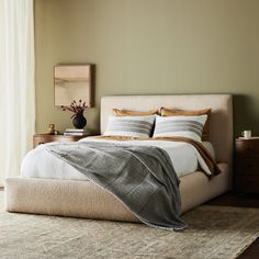 a bedroom with a bed, nightstands and window in the background on a carpeted floor