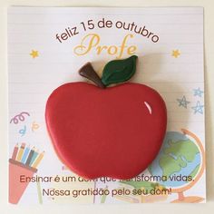 a red apple brooch sitting on top of a piece of paper with writing underneath it