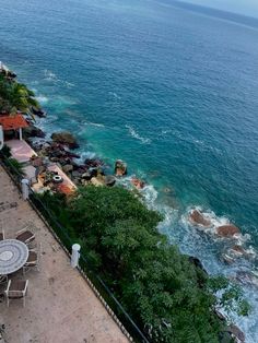 an outdoor dining area overlooking the ocean with tables and chairs