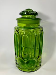 a green glass jar sitting on top of a white table