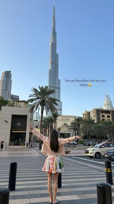 a woman standing in front of a tall building with her arms spread out to the side