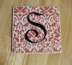 the letter s is on top of an orange and white square with black swirls