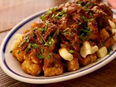 a white plate topped with meat and potatoes covered in gravy on top of a wooden table