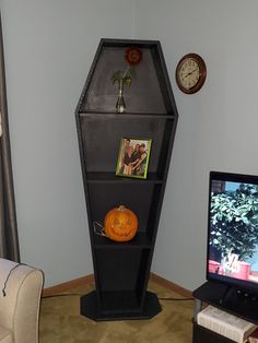 a television sitting next to a tall black shelf with pictures on it's sides