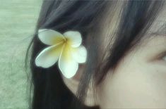 a close up of a person's face with a flower in the middle of her ear