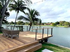 a wooden deck next to a body of water with palm trees on the other side