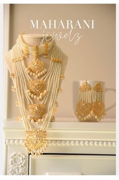 the necklace and earrings are on display in front of a white fireplace mantel with gold accents