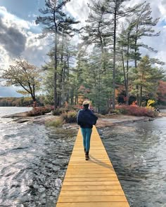 a person walking across a wooden bridge over water