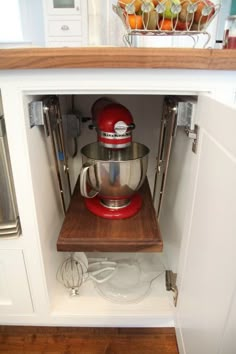 an open kitchen cabinet with a red blender