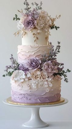 a three tiered cake decorated with flowers and greenery