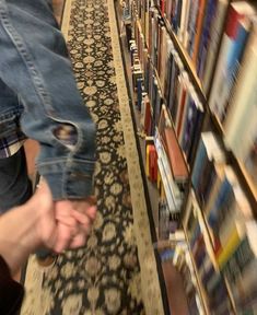 a person holding onto a pair of jeans in front of a book shelf filled with books