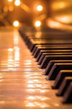 a close up view of a piano with lights in the background