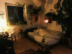 a bed sitting in the middle of a living room next to a window with plants on it