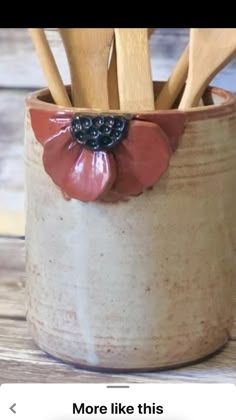 a cup with wooden utensils in it and a flower decoration on the side