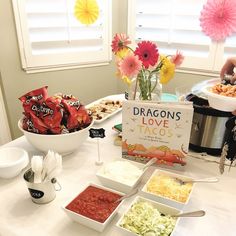 a table topped with lots of food next to a sign that says dragon's love tacos