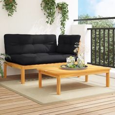 a black couch sitting on top of a wooden floor next to a table and potted plants