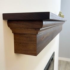 a close up of a wooden shelf on the wall with a fireplace in the background