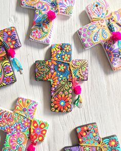 colorful crosses with tassels and pom - poms laid out on a white surface