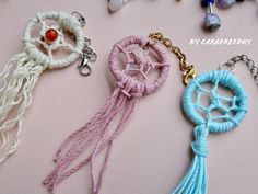 three key chains with beads and tassels hanging from them on a pink surface