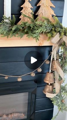 a mantel decorated with evergreen and bells