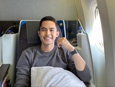 a man sitting in an airplane with his arm around the back of him and smiling at the camera