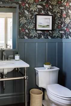 a bathroom with blue walls and floral wallpaper on the walls, along with a white toilet and sink