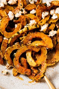 roasted squash with feta cheese and herbs on a white platter, ready to be eaten