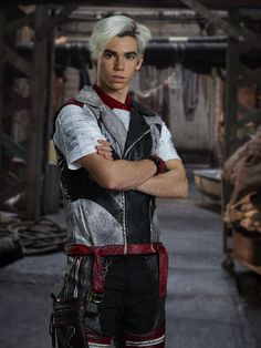 a young man with white hair wearing a leather vest and holding his arms crossed in front of him