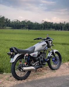 the motorcycle is parked on the side of the road in front of some rice fields