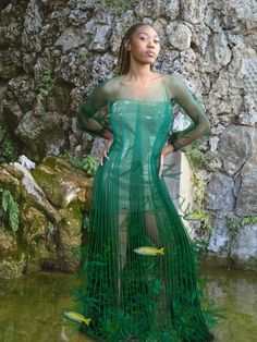 a woman standing in the water wearing a green mesh dress with fish net on it