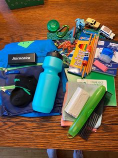 the contents of a backpack laid out on top of a wooden table next to a blue bag